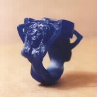 Wax carving of happy mermaids holding horseshoe ring.